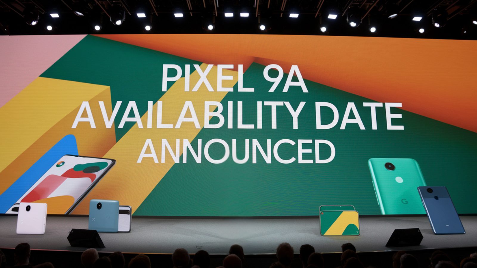 The image shows the Google Pixel 9a smartphone on a background, highlighting its sleek design and modern aesthetics. The display features the words "Available Now," emphasizing the newly announced availability date following previous delays.